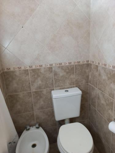 a bathroom with a toilet and a tiled wall at San Remo World Hotel in San Clemente del Tuyú