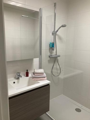 een witte badkamer met een douche en een wastafel bij West-Ende in Middelkerke