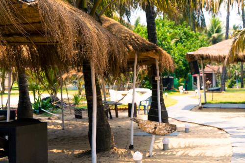 a resort with a straw umbrella and a chair at Village Susegat Beach Resort in Morjim