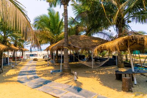 a resort with palm trees and a hammock on the beach at Village Susegat Beach Resort in Morjim