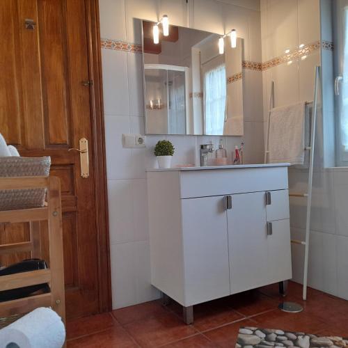 a white bathroom with a sink and a mirror at Mirador de Garabandal in San Sebastián de Garabandal