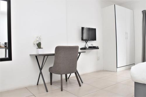 a room with a desk with a chair and a television at Cosmo Sleepover in Roodepoort