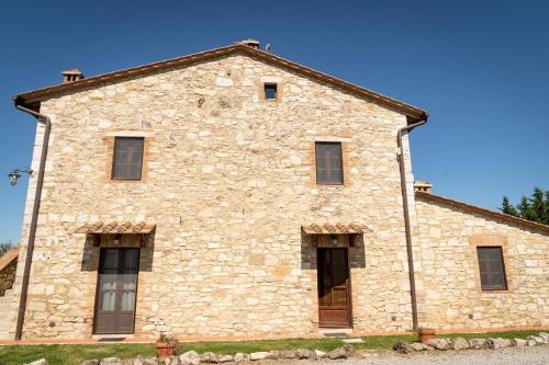 an old stone building with windows and a blue sky at Podere Sant'Antonio in Asciano