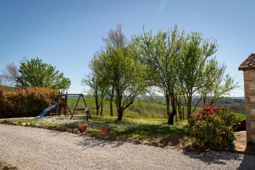 a park with a playground with a slide and trees at Podere Sant'Antonio in Asciano