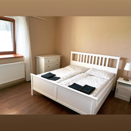 a bedroom with a white bed with two tables and a window at Chalupa u lesa - Nova Ves in Český Rudolec