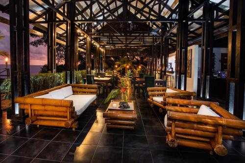 a restaurant with couches and tables on a patio at Tiki Villas Rainforest Lodge - Adults Only in Uvita