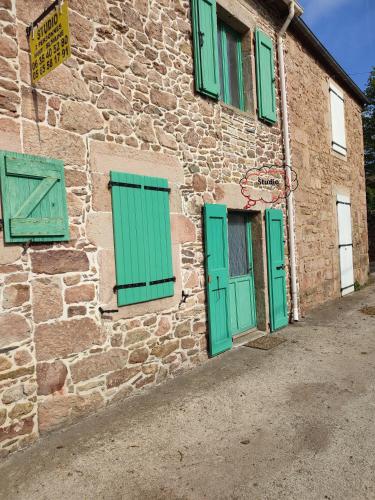 een stenen gebouw met groene deuren en ramen bij Studio plain-pied in Montjaux