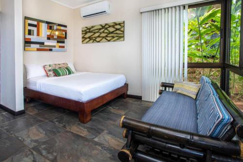 a bedroom with a bed and a couch and a window at Tiki Villas Rainforest Lodge - Adults Only in Uvita