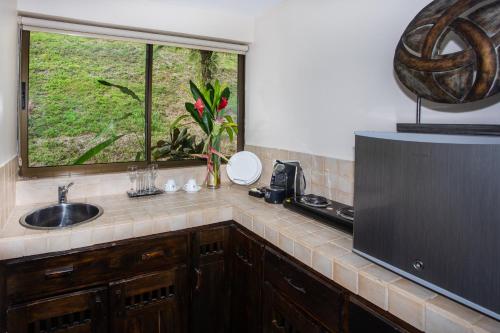 a kitchen with a sink and a window at Tiki Villas Rainforest Lodge - Adults Only in Uvita