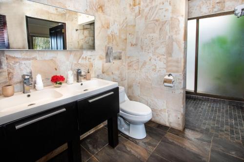 a bathroom with a sink and a toilet and a mirror at Tiki Villas Rainforest Lodge - Adults Only in Uvita