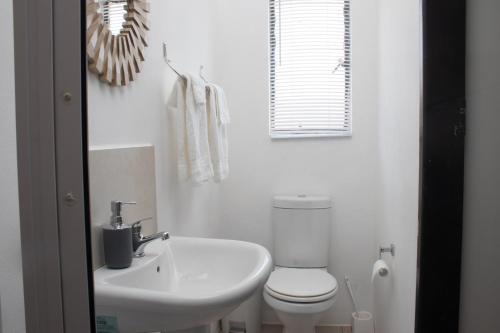 a white bathroom with a sink and a toilet at Cosmo Sleepover in Roodepoort