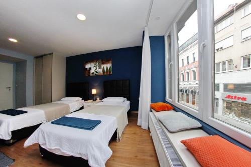 Habitación con 4 camas y ventana grande. en Apartmani BarSa, en Sarajevo