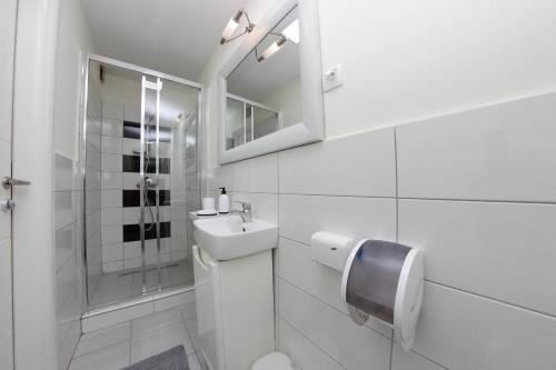 Un baño blanco con lavabo y ducha en Apartmani BarSa, en Sarajevo