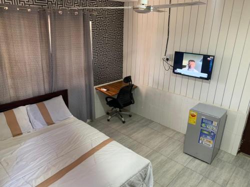 a bedroom with a bed and a desk and a tv at MAXJEN HAVEN GUEST HOUSE in Kasoa