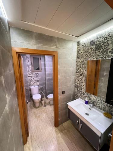 een badkamer met een toilet, een wastafel en een spiegel bij Villa Haitam Marrakech in Oubadine