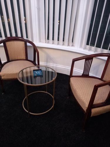 two chairs and a table in a room with windows at The Gatsby Blackpool - Formerly The Windsor in Blackpool
