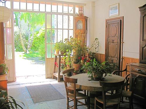 a dining room with a table with chairs and a clock at Relais de Poste in Janville