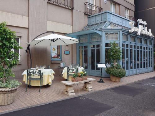 a restaurant with a table and an umbrella on a sidewalk at Hotel Monterey Lasoeur Ginza in Tokyo