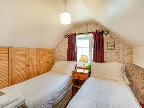 Duas camas num pequeno quarto com uma janela em Halfen Granary em Llanfihangel-yng-Ngwynfa