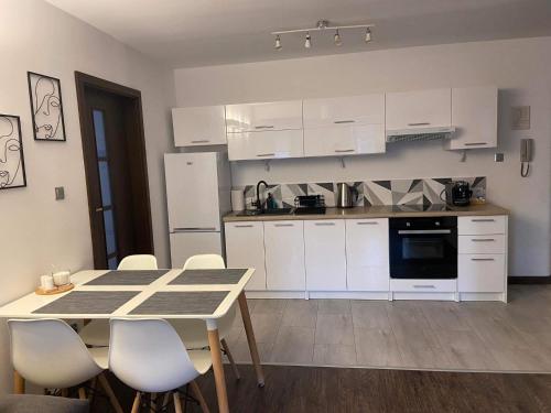 uma cozinha com armários brancos e uma mesa e cadeiras em Apartament Ełk Centrum em Ełk