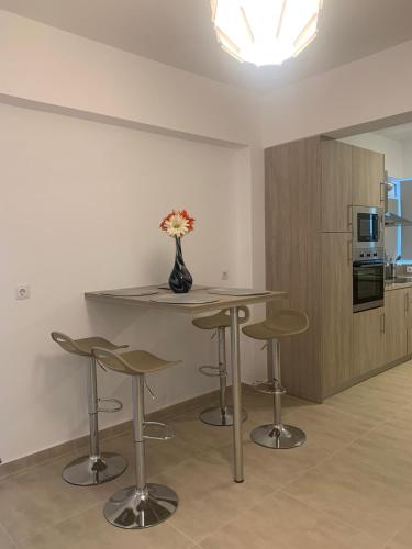 a kitchen with a table with stools and a vase with flowers at KOS SUITE HOME in Platánion