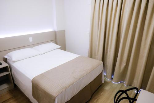 a small bedroom with a bed and a curtain at Hotel do Gringo in Erval Velho