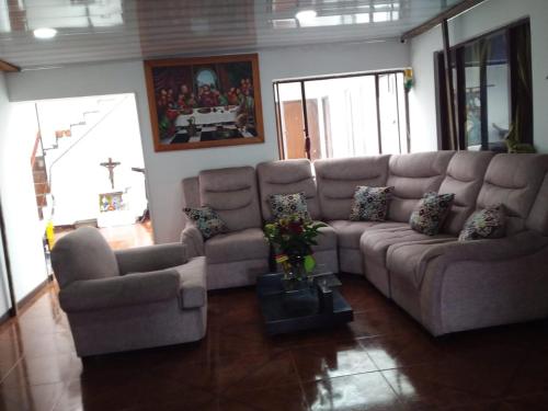 ein Wohnzimmer mit einem großen Sofa und Stühlen in der Unterkunft Habitación con baño privado cerca al aeropuerto in Bogotá