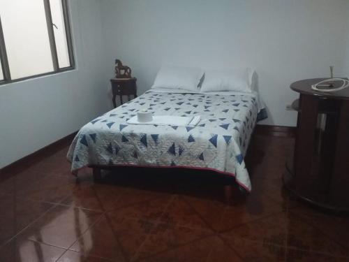 um quarto com uma cama com um cobertor em Habitación con baño privado cerca al aeropuerto em Bogotá