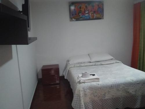 Un pequeño dormitorio con una cama con una taza. en Habitación con baño privado cerca al aeropuerto, en Bogotá