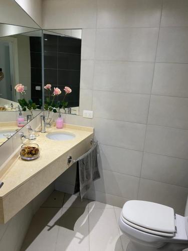 a bathroom with a sink and a toilet and a mirror at Wind Tower Punta del Este in Punta del Este
