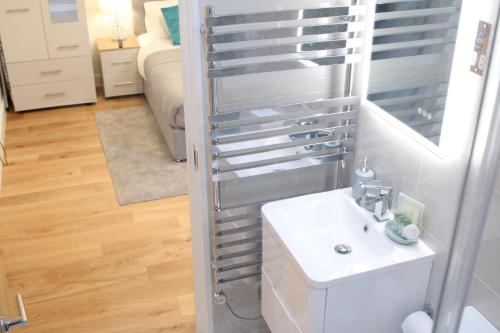 a bathroom with a white sink and a mirror at High Spec Luxury Studio Apartment in Sydenham in Sydenham