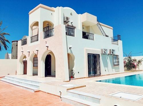 a white house with a swimming pool in front of it at Villa Tezdain in Houmt Souk