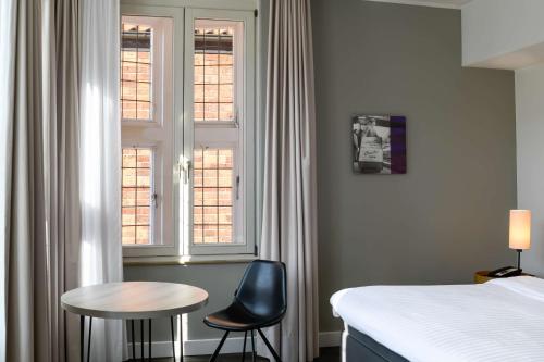 a bedroom with a bed and a table and two chairs at Radisson Blu Hotel Bremen in Bremen
