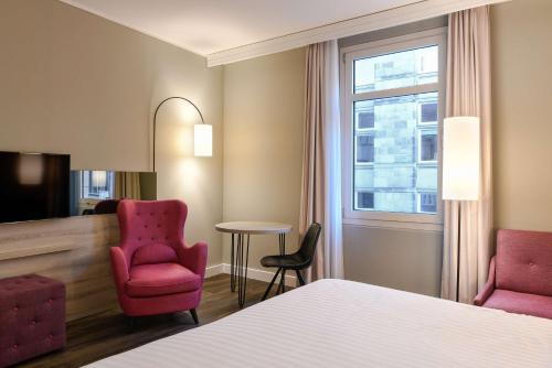 a hotel room with a bed and two chairs and a table at Radisson Blu Hotel Bremen in Bremen