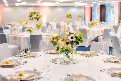 a room with white tables and chairs with vases of flowers at Radisson Blu Hotel Bremen in Bremen