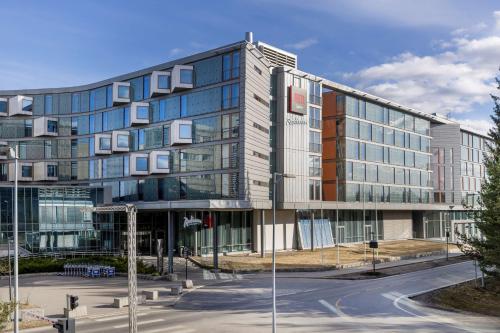 a large glass building with a street in front of it at Radisson Hotel & Conference Centre Oslo Airport in Gardermoen