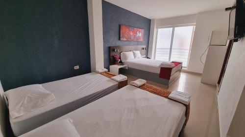 a bedroom with two beds and a large window at Magdalena Imperial Hotel By GHO Hoteles in Girardot