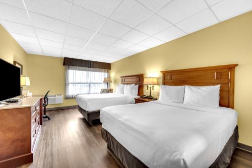 a hotel room with two beds and a flat screen tv at The Academy Hotel Colorado Springs in Colorado Springs