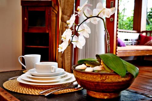 a table with a bowl with a vase with white flowers at Kampung Sumber Alam Garut in Garut