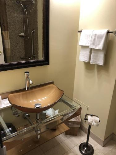 a bathroom with a sink and a mirror and towels at The Academy Hotel Colorado Springs in Colorado Springs