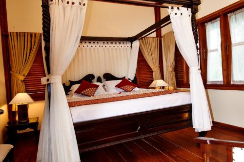 a bedroom with a canopy bed with curtains at Kampung Sumber Alam Garut in Garut