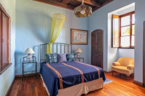 a bedroom with a bed and a chair at Casa Los Jardínes in Antigua Guatemala