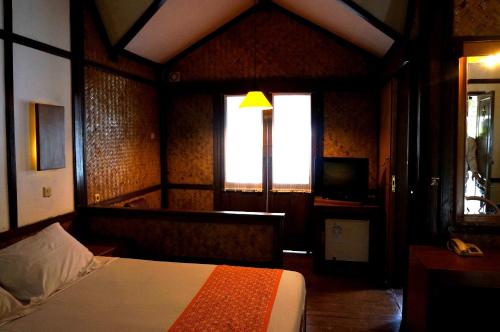 a bedroom with a bed and a window and a television at Kampung Sumber Alam Garut in Garut