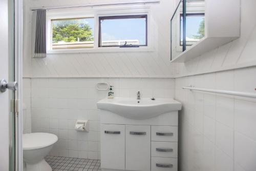 a bathroom with a sink and a toilet and two windows at Beach Haven in Hawks Nest