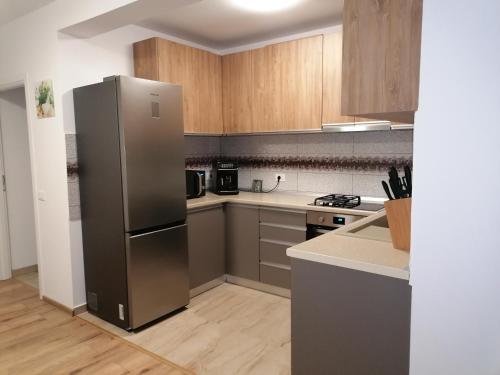 a kitchen with a stainless steel refrigerator and wooden cabinets at Agropensiunea Vila Cristina in Niculiţel