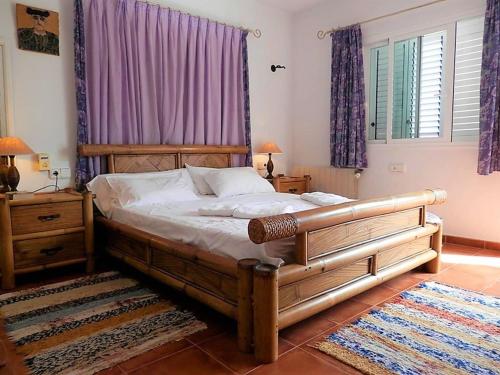 a bedroom with a large wooden bed with purple curtains at Villa in Ibiza with Private Pool in Santa Eularia des Riu