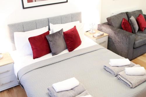 a bedroom with a large bed with red pillows and a couch at Executive Bright and Airy Studio Apartment in Sydenham in London