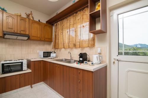 a kitchen with wooden cabinets and a sink and a window at En Elladi Apartment in Alikanas