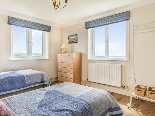 Un dormitorio con dos camas y dos ventanas. en Penhallick House, en Tintagel