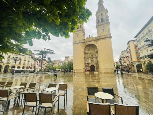 un gruppo di tavoli e sedie di fronte a una torre dell'orologio di Laurel centro a Logroño